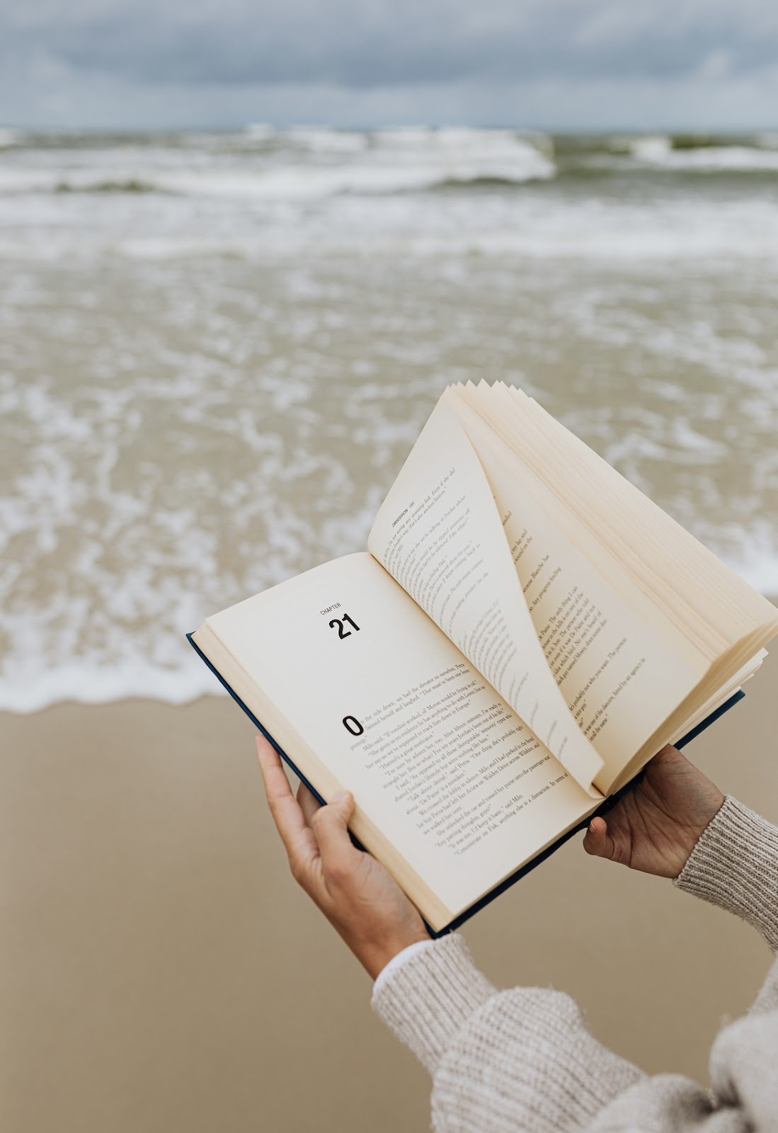Sea and book on somebody’s hands.