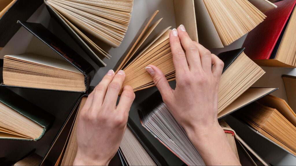 a close-up shot of hands touching vertically standing books