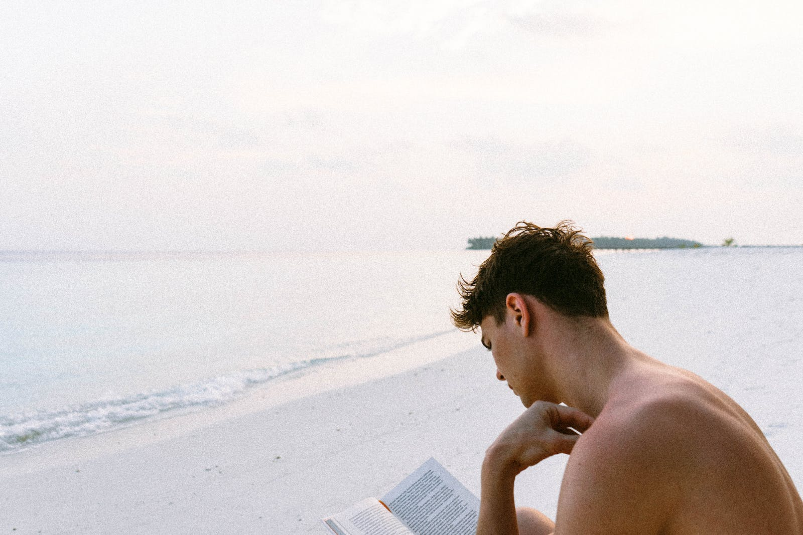 Guy reading a book on the beach