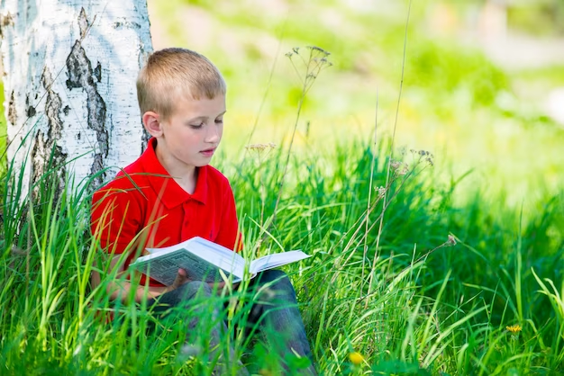 Boy reading a book under a tree