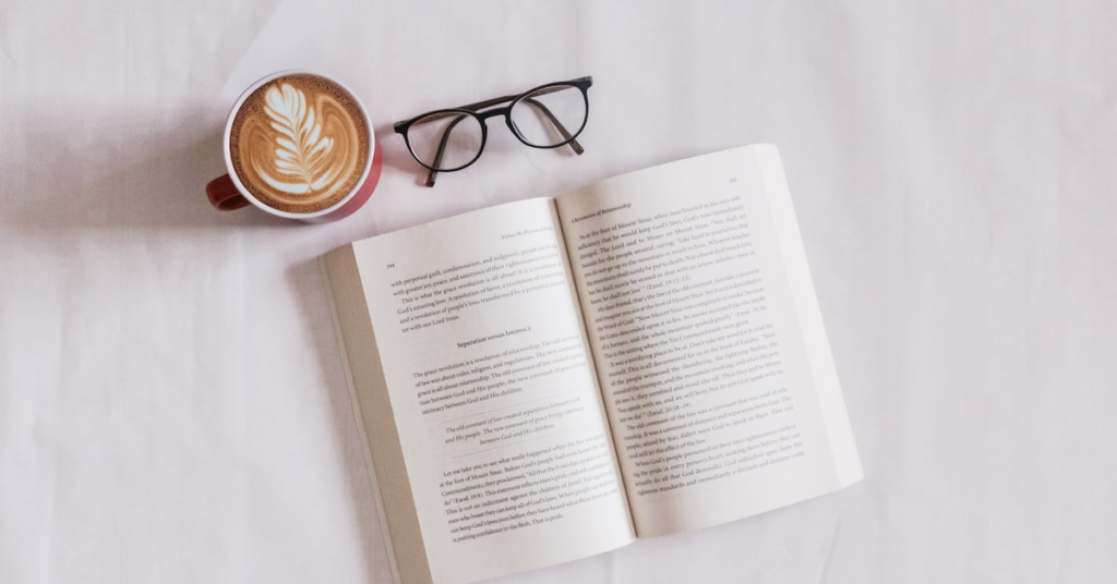 Open book next to coffee and glasses
