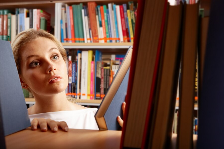 Image of a woman searching for a book on a bookshelf