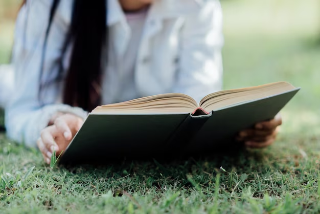 Girl reading book on grass